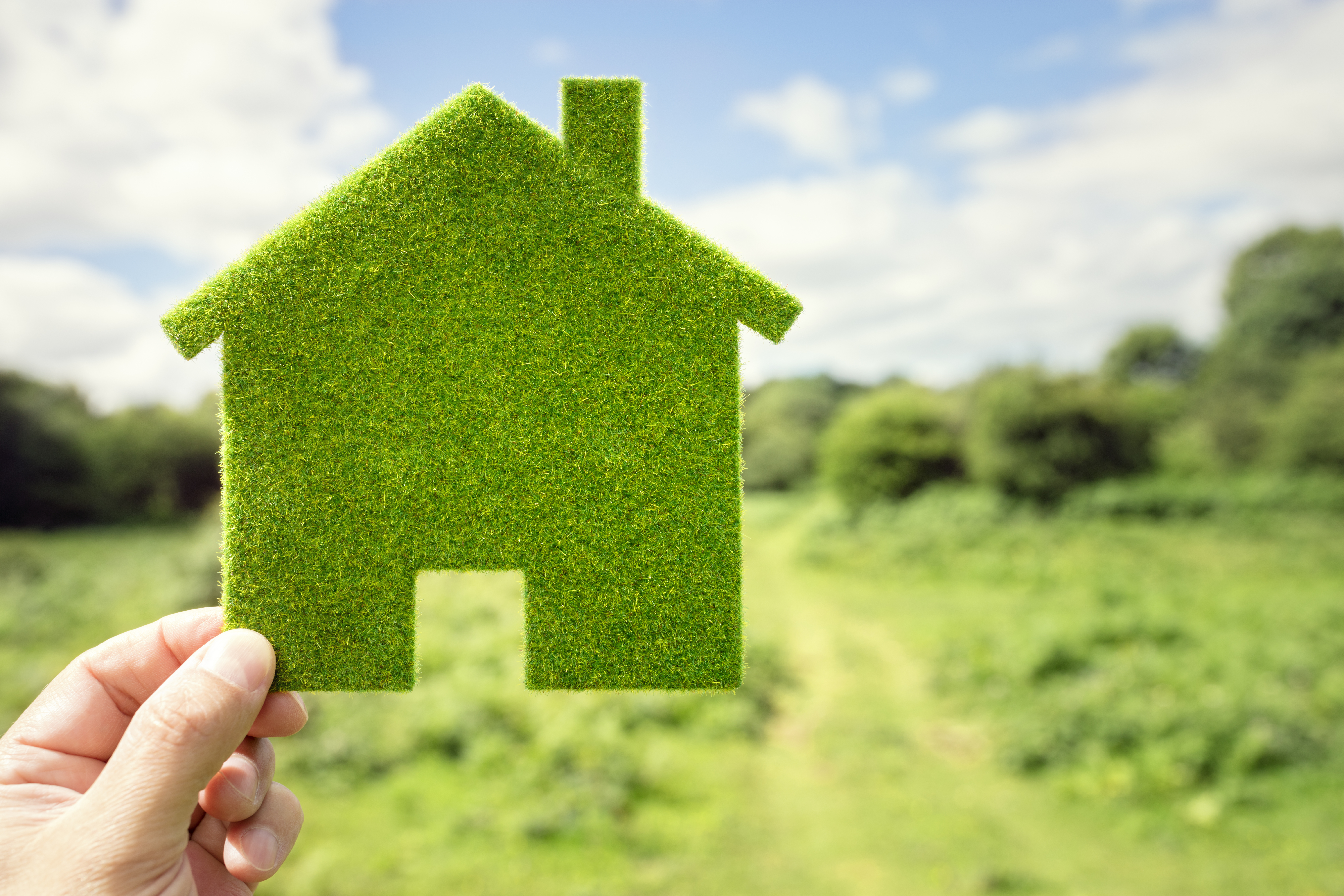 hand holding up cutout of green house