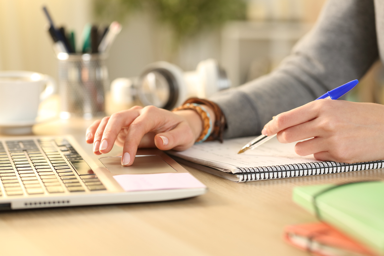 closeup of woman's hands writing in notebook